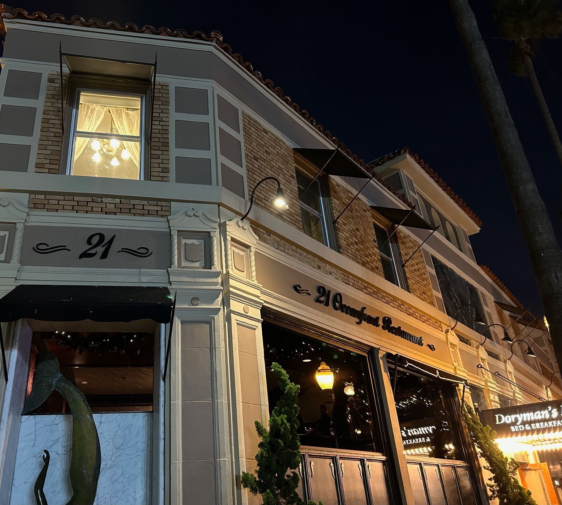 Restaurant building at night, corner view with awnings, lights, and signage. 