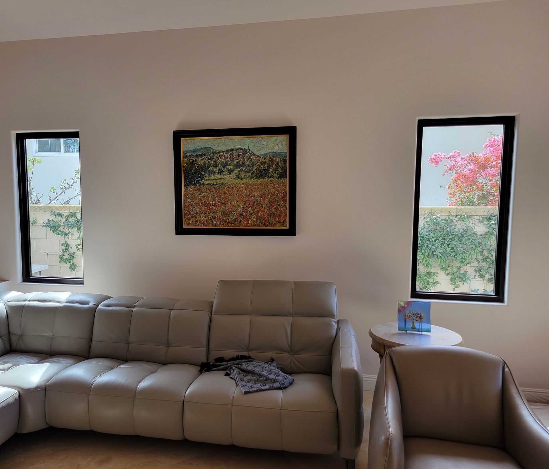 Living room with a beige couch, windows, and art.