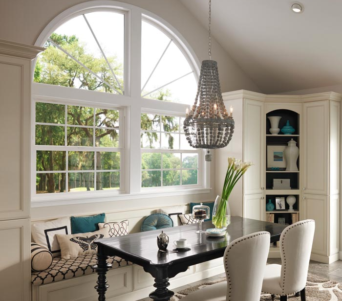 Dining room with large window, built-in bench seating, chandelier, and a black table.