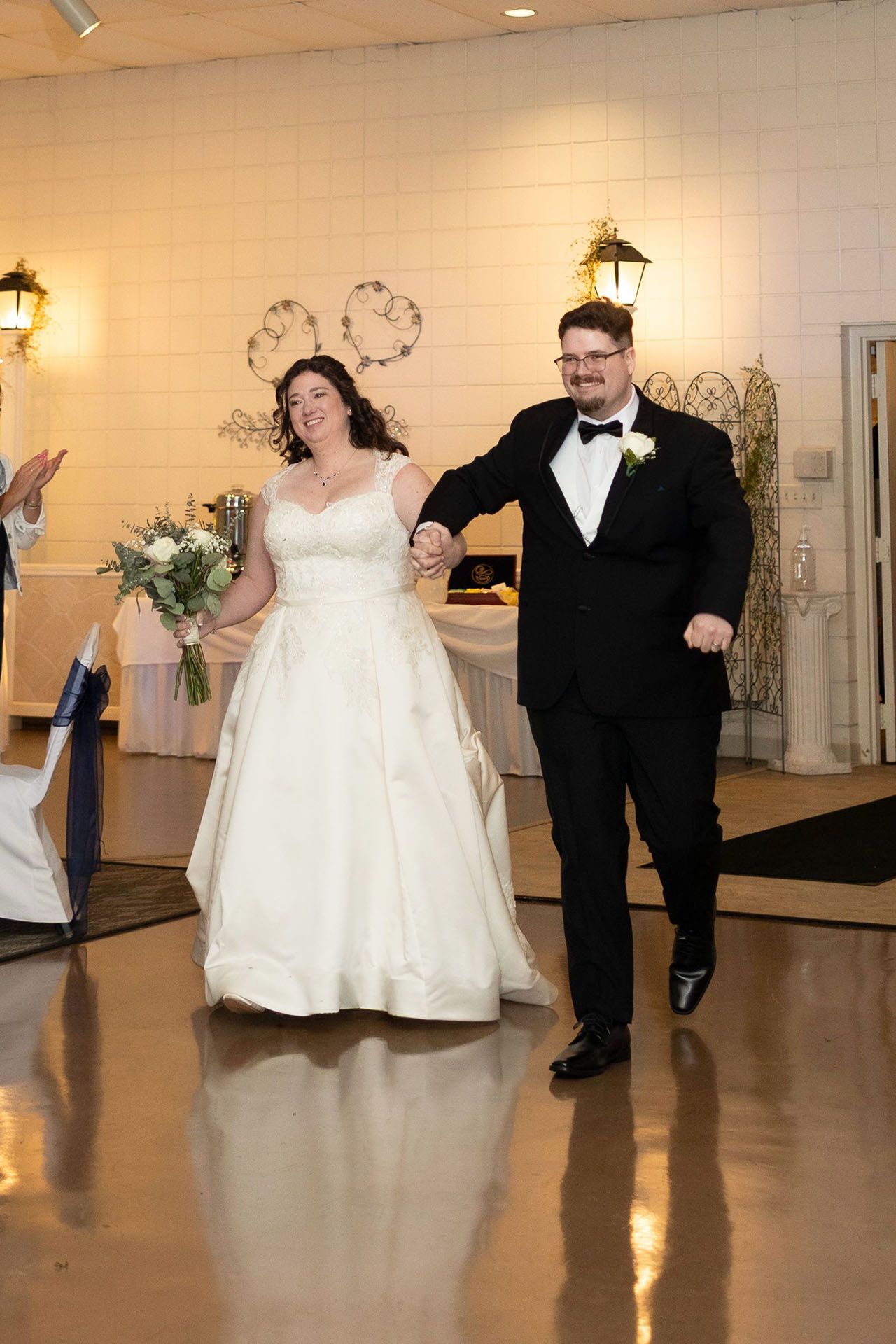 Bride and groom entering a reception hall, smiling and holding hands