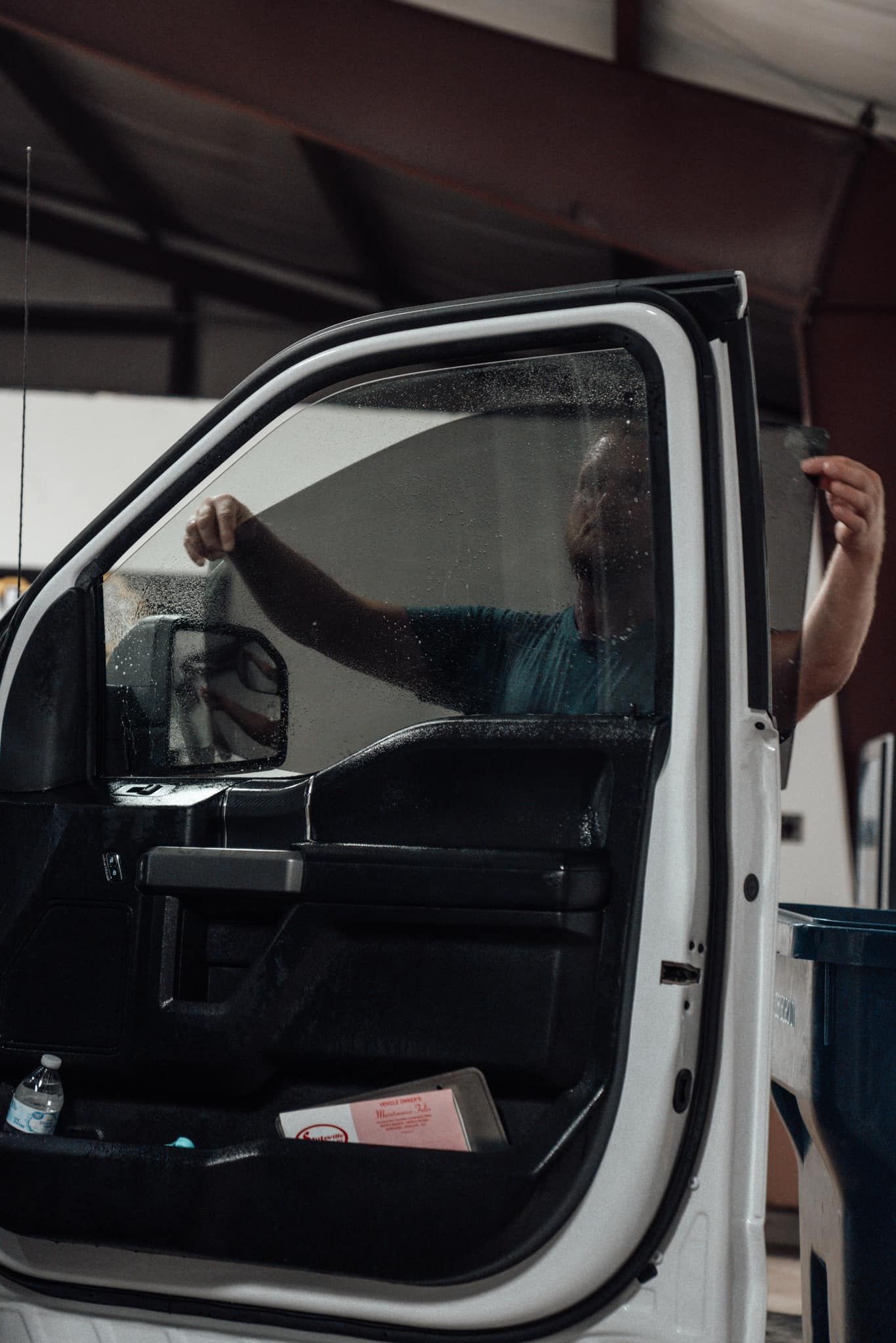 A man is applying window tinting to a white truck.