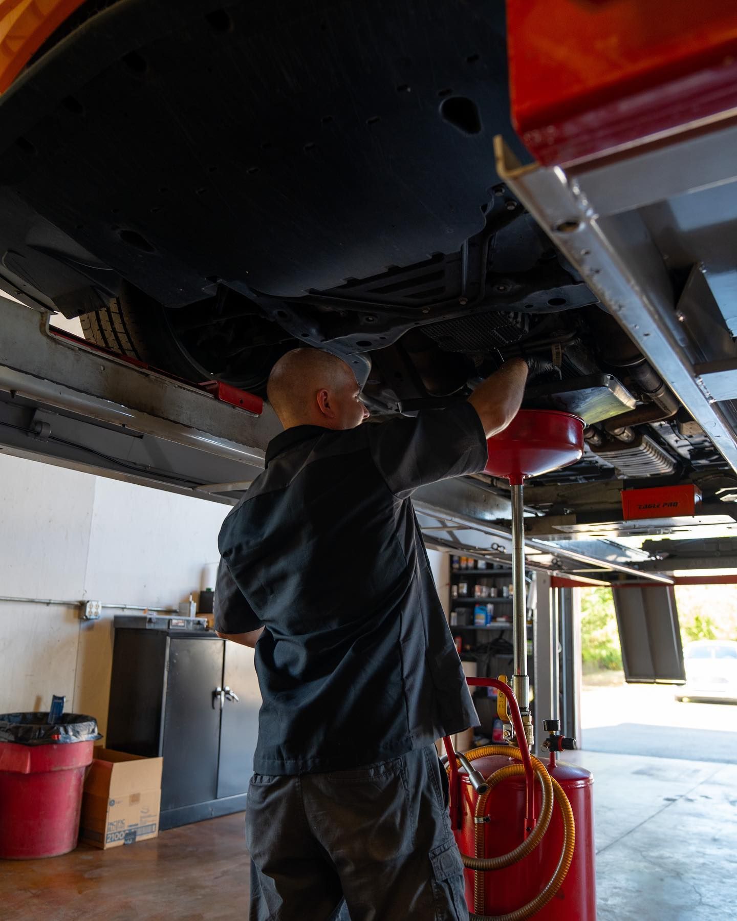 A man is working under a car in a garage.