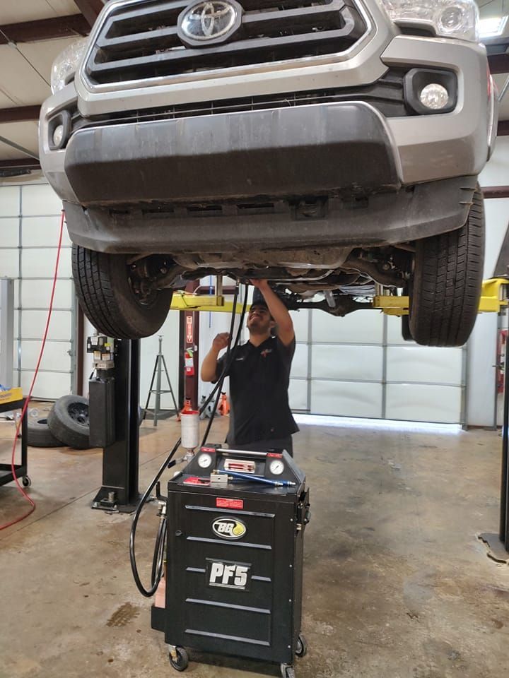 A man is working under a truck on a lift in a garage.