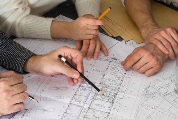 Hands pointing at blueprints, discussing a project.