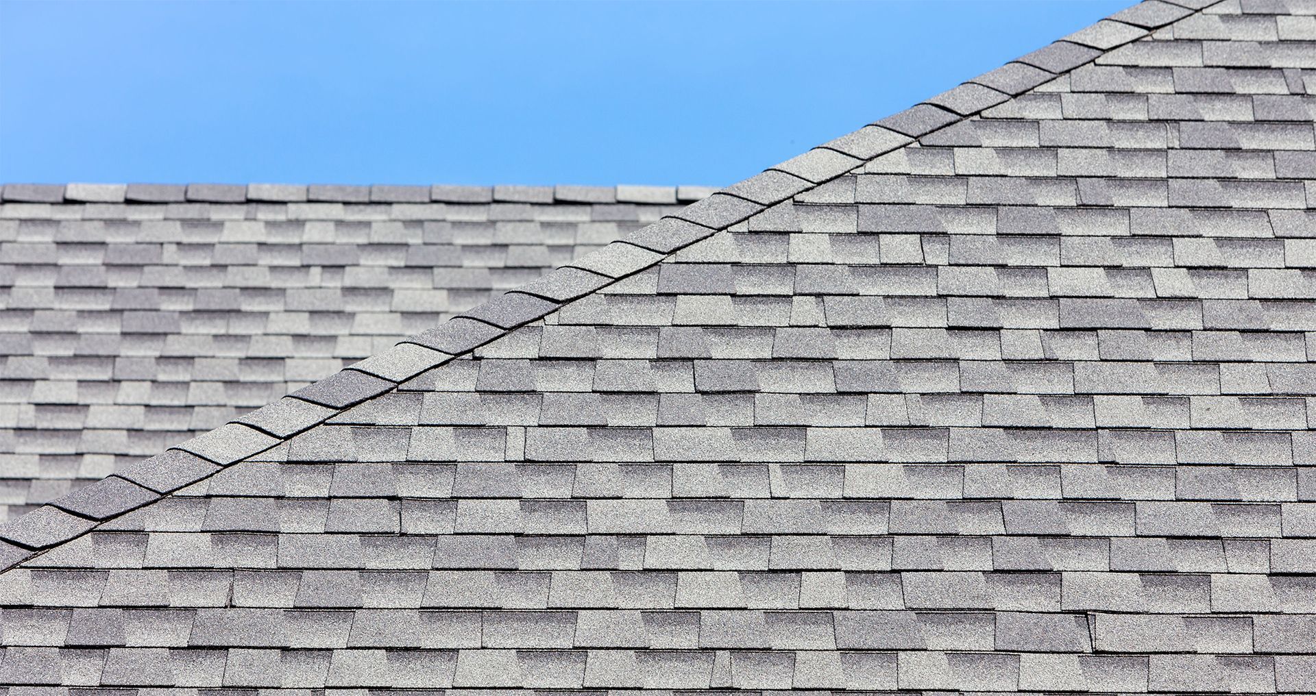 Gray asphalt shingle roof against a blue sky.