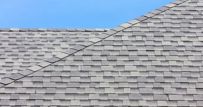 Gray asphalt shingle roof against a blue sky.