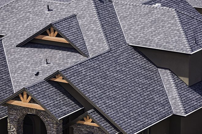 Gray asphalt shingle roof on a house with stone and wooden accents.