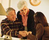 Elderly couple shaking hands with an attorney