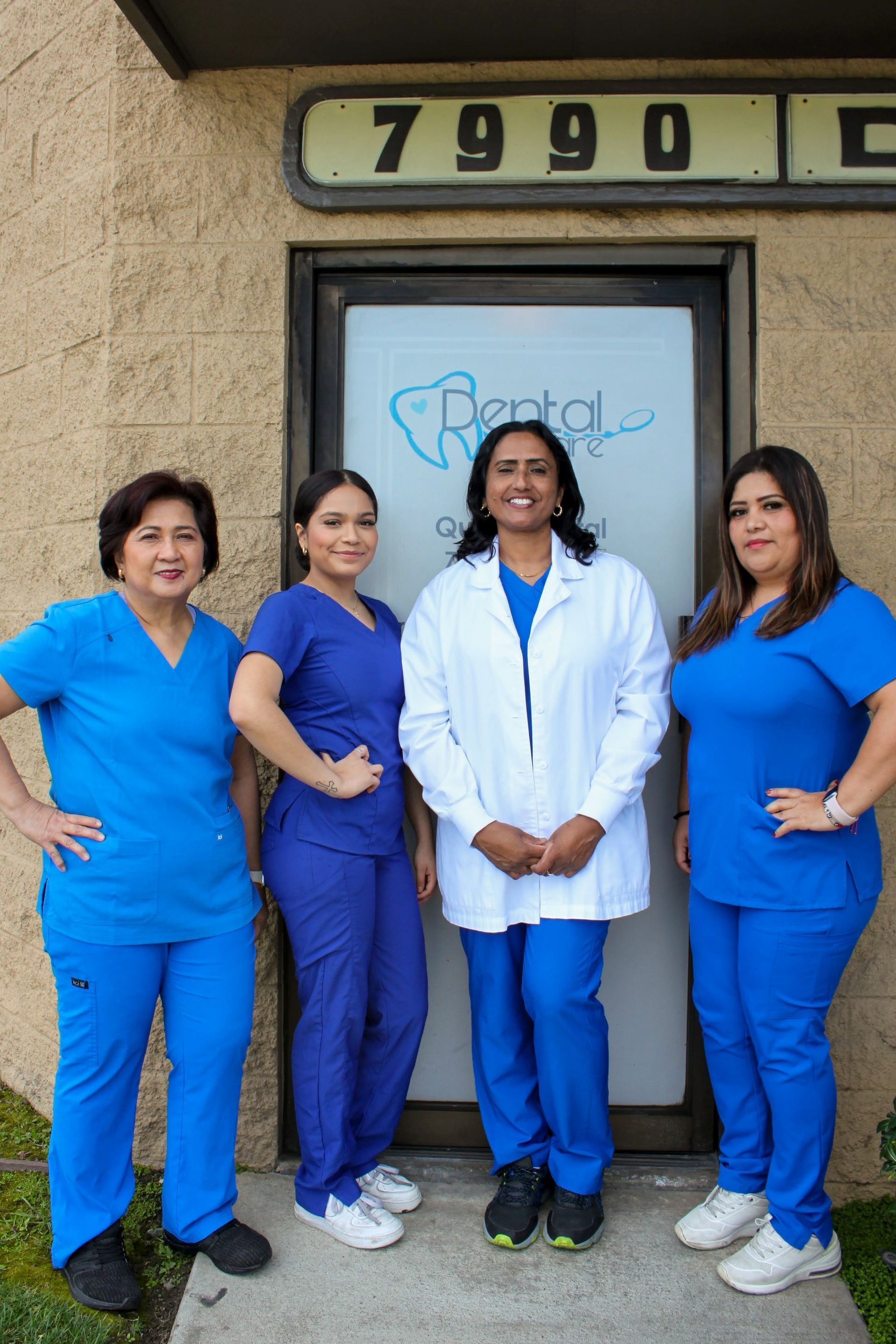 A group of women in blue scrubs are posing for a picture in front of a building