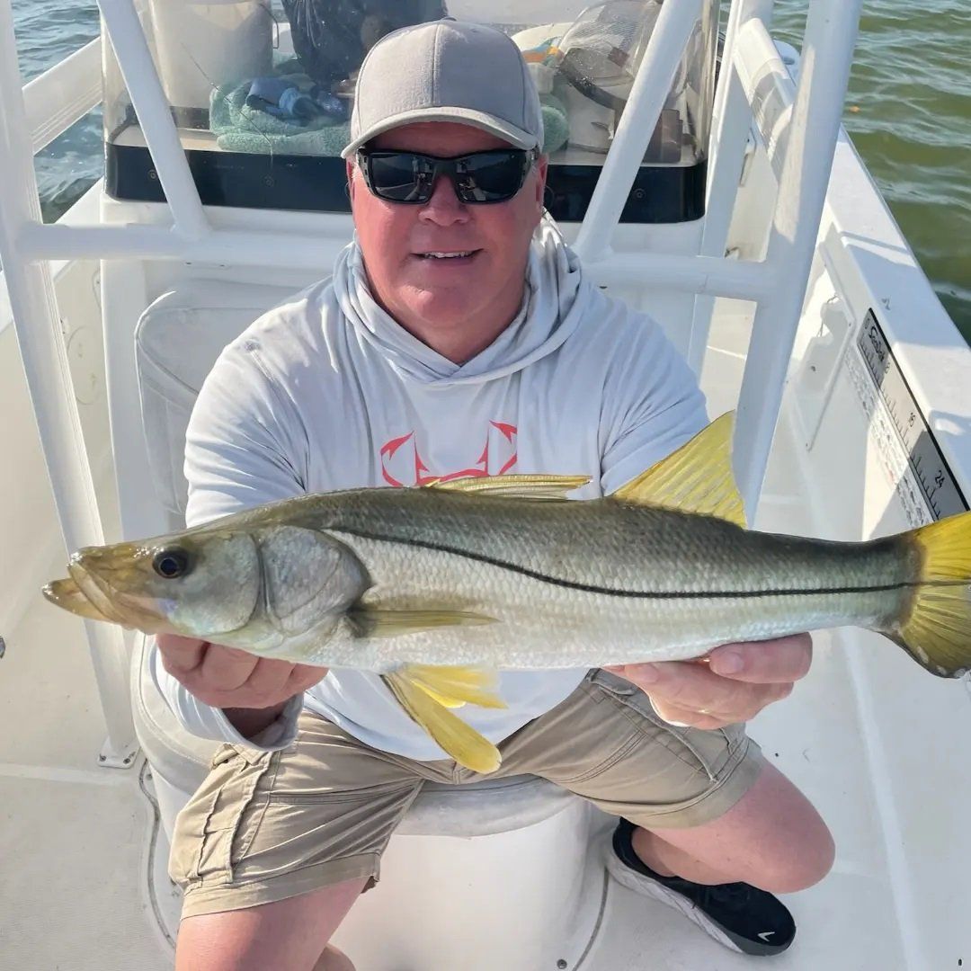 man with cap and shades holding angler catch