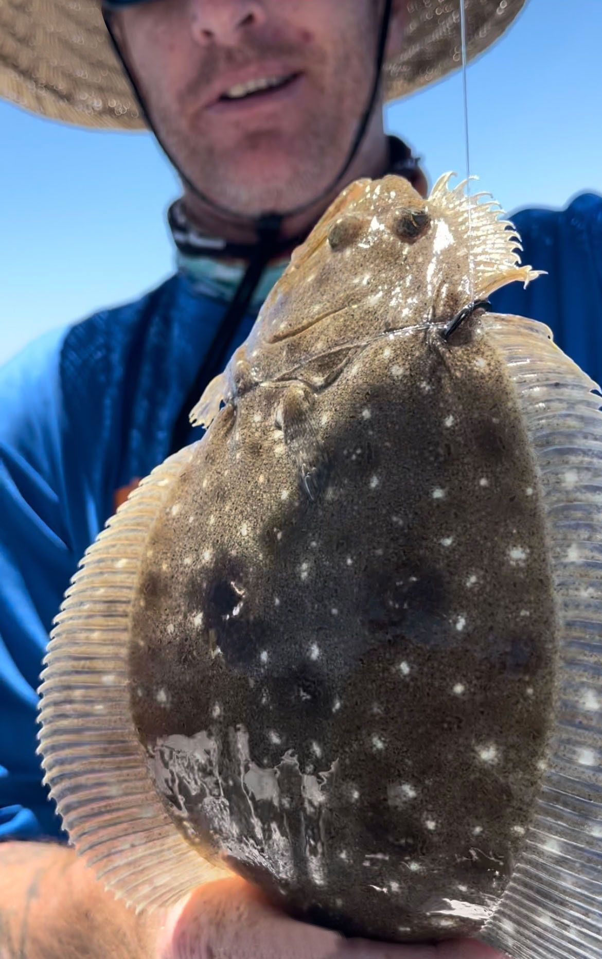A man in a hat is holding a fish in his hands