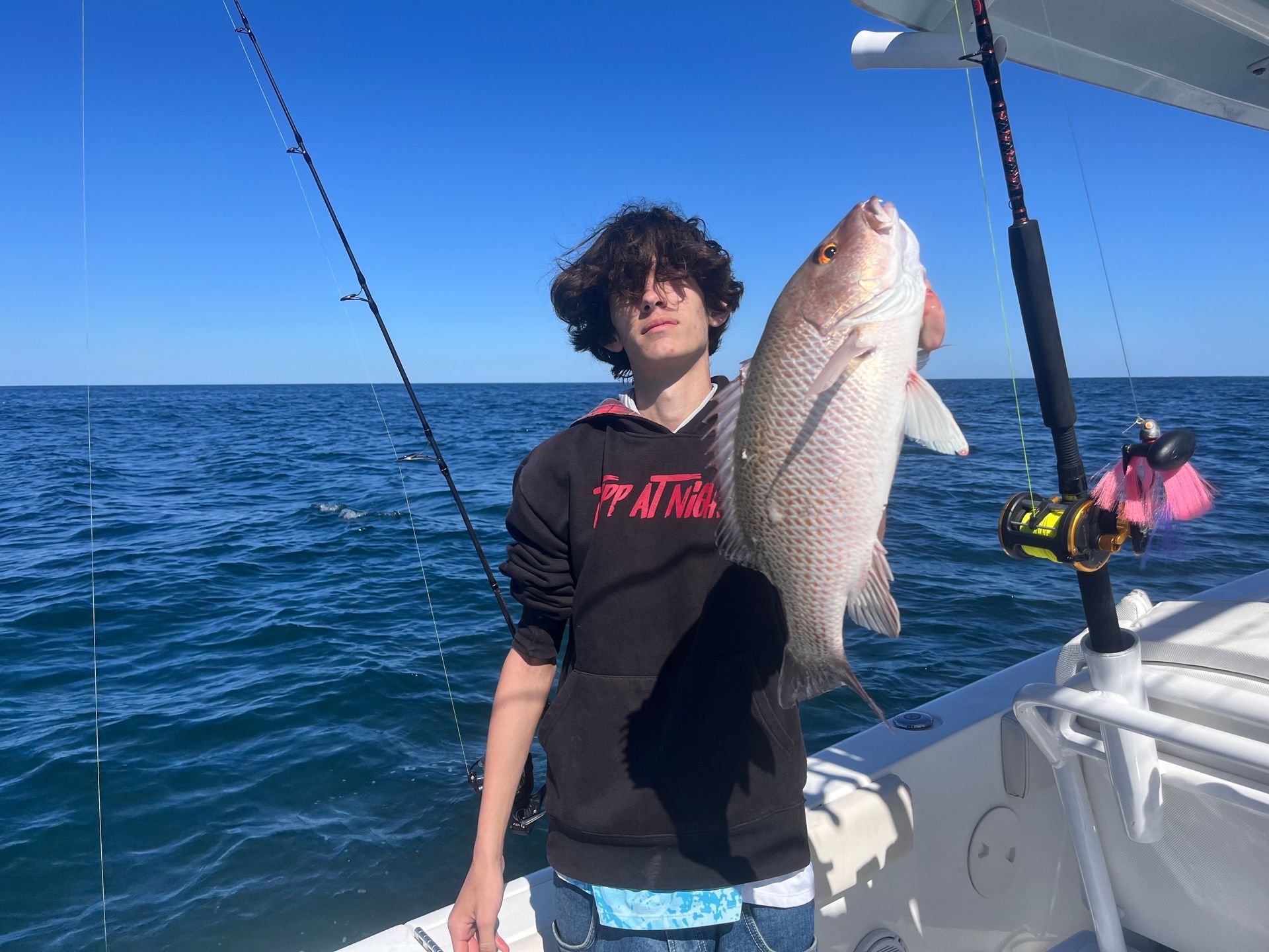 A young boy is holding a large fish on a boat