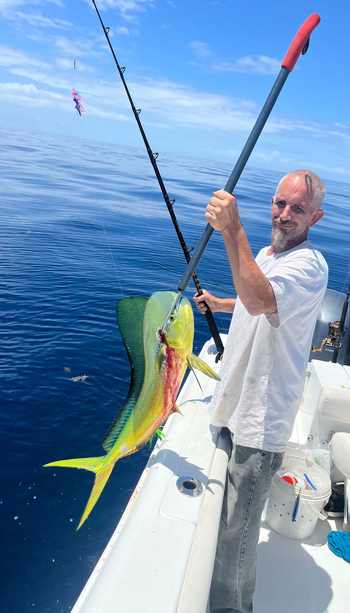 A man is holding a fish on a boat in the ocean