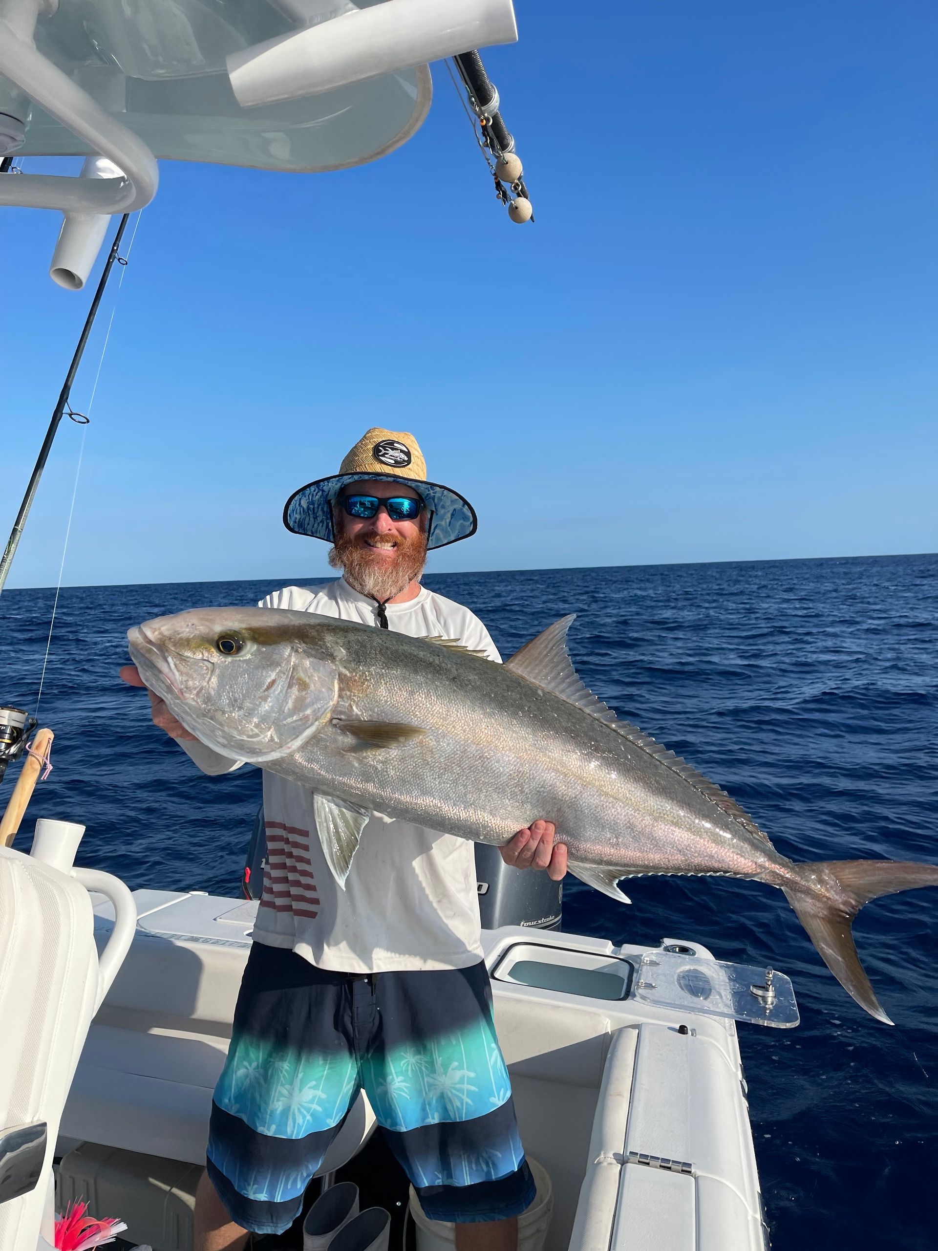A man is holding a large fish on a boat in the ocean