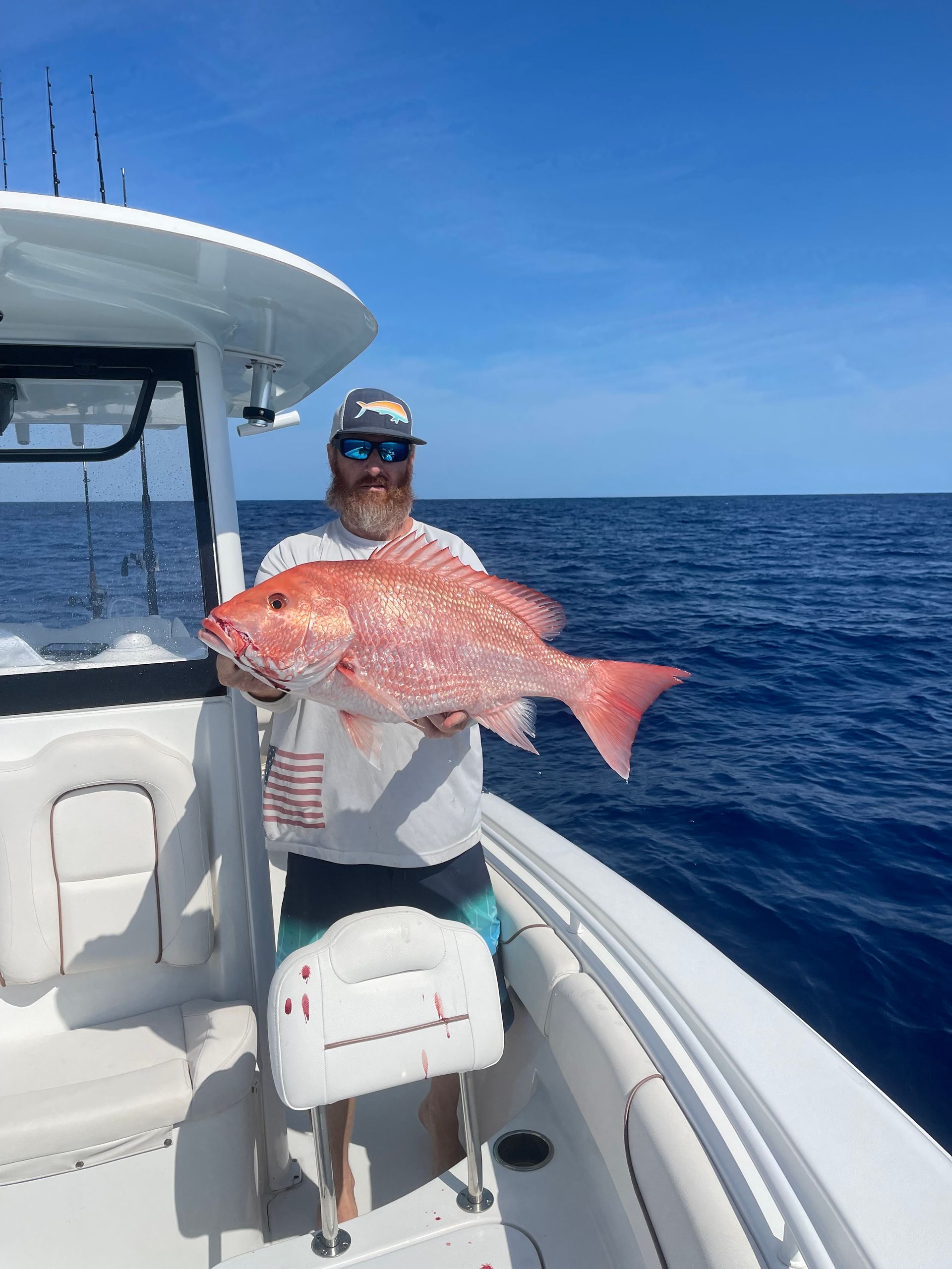 A man is holding a large red fish on a boat in the ocean