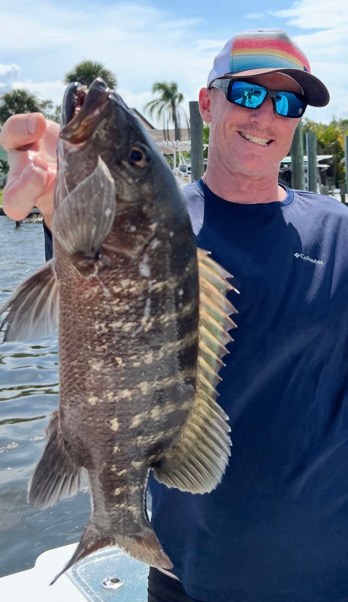 A man is holding a large fish in his hand on a boat
