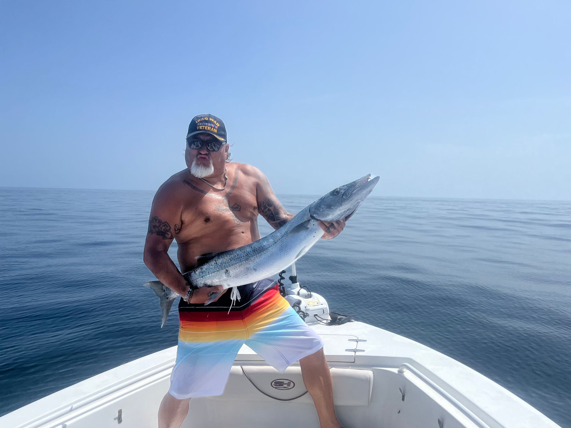 A man is standing on a boat holding a large fish