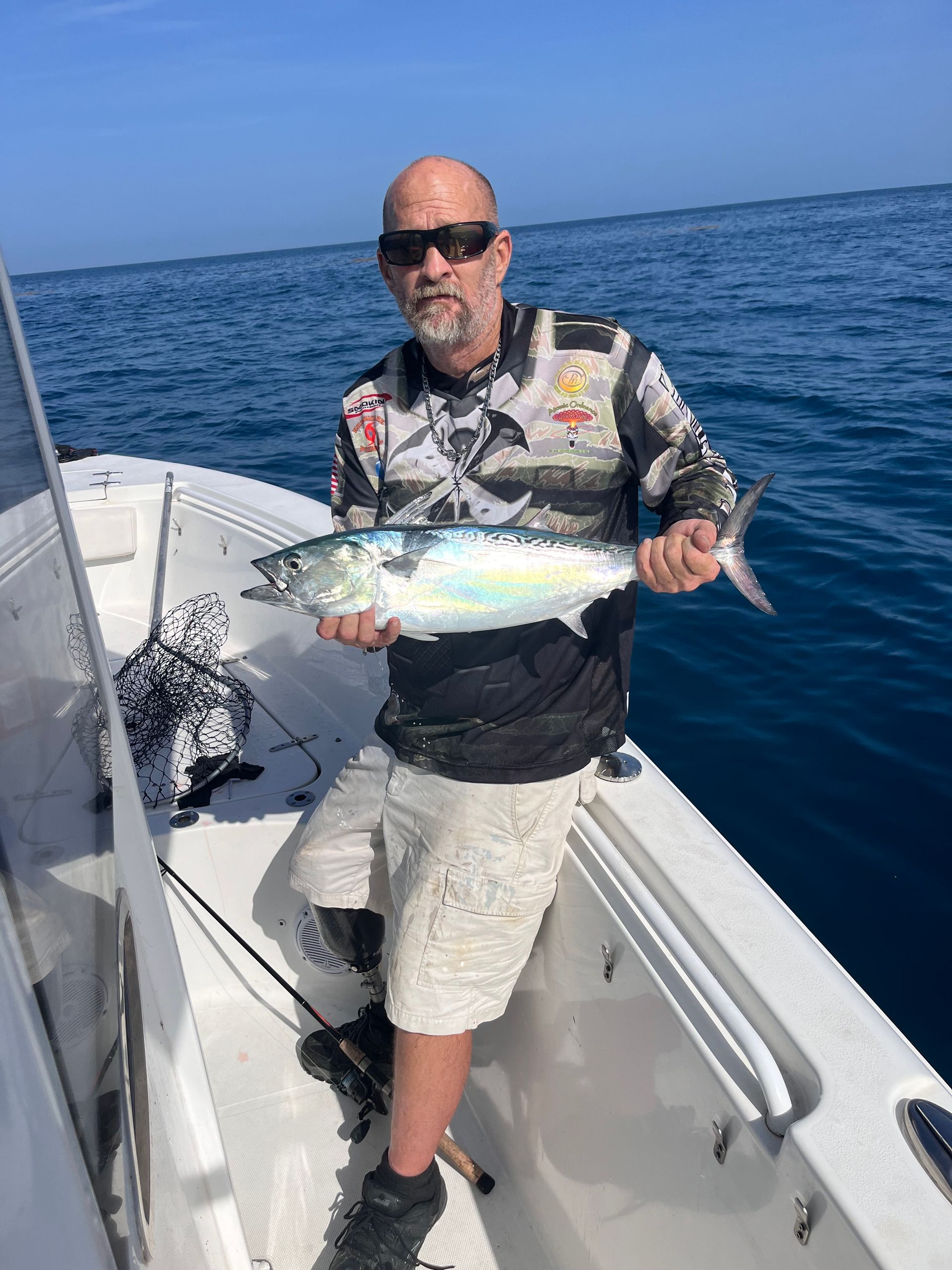A man is holding a fish on a boat in the ocean