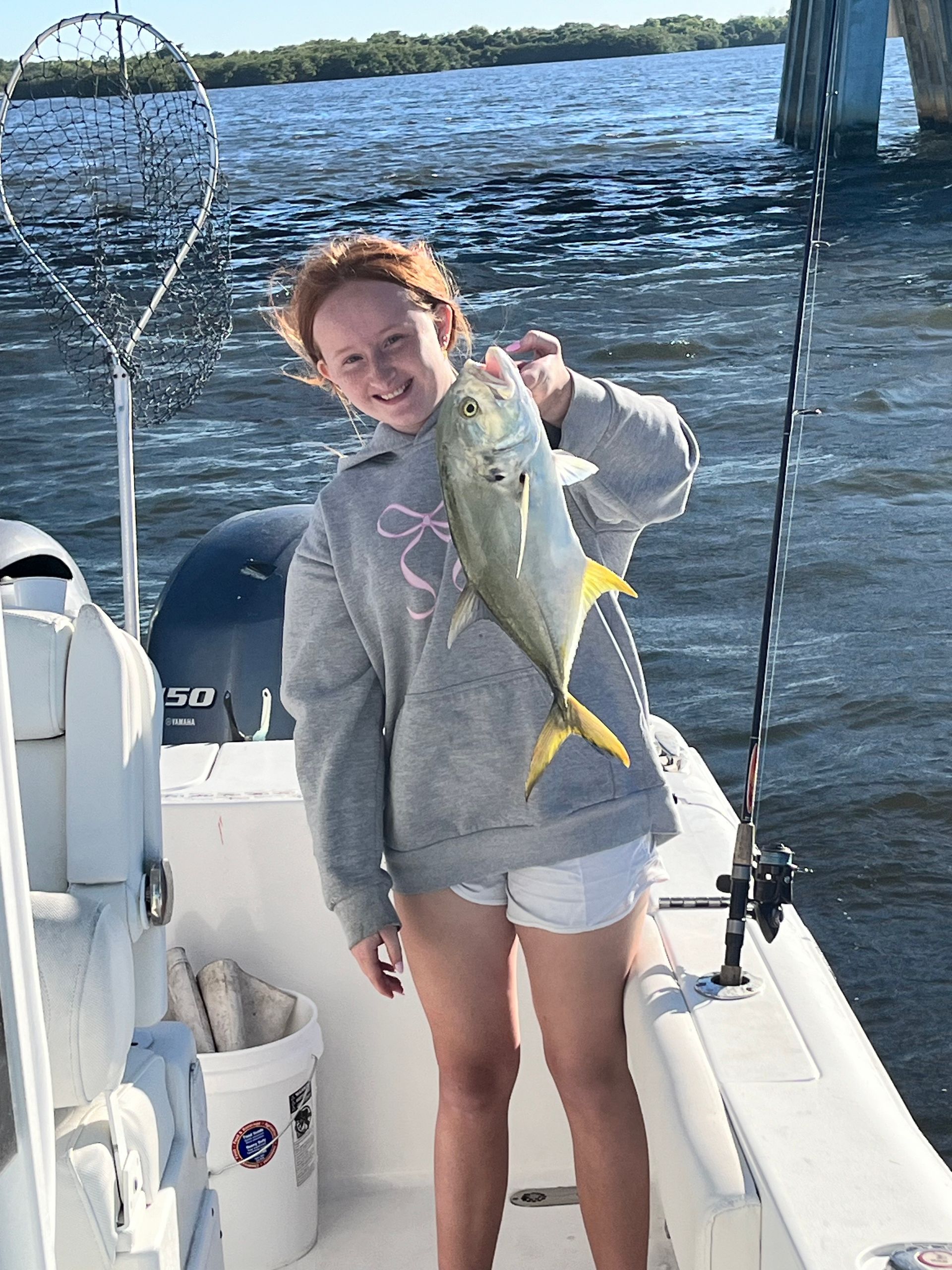 A young girl is standing on a boat holding a fish