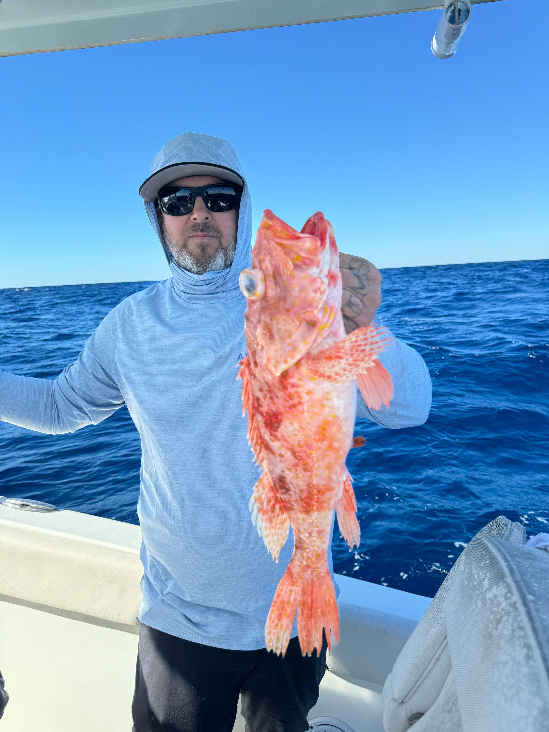 A man is holding a large red fish on a boat in the ocean