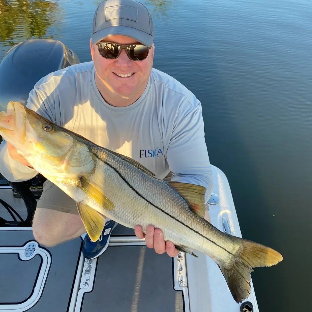 man on gray shirt and cap smiling with big fish