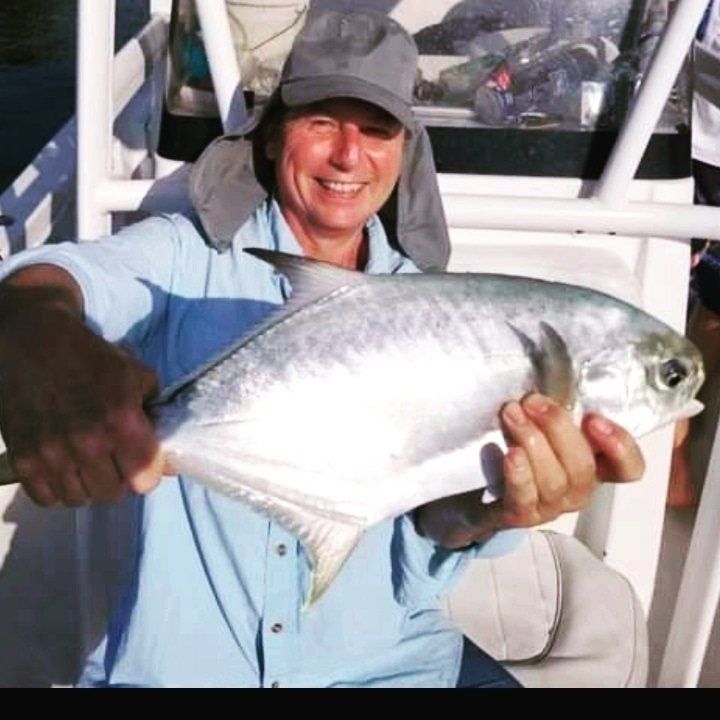 man on hat smiling holding fish