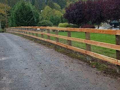 A wooden fence is along the side of a road