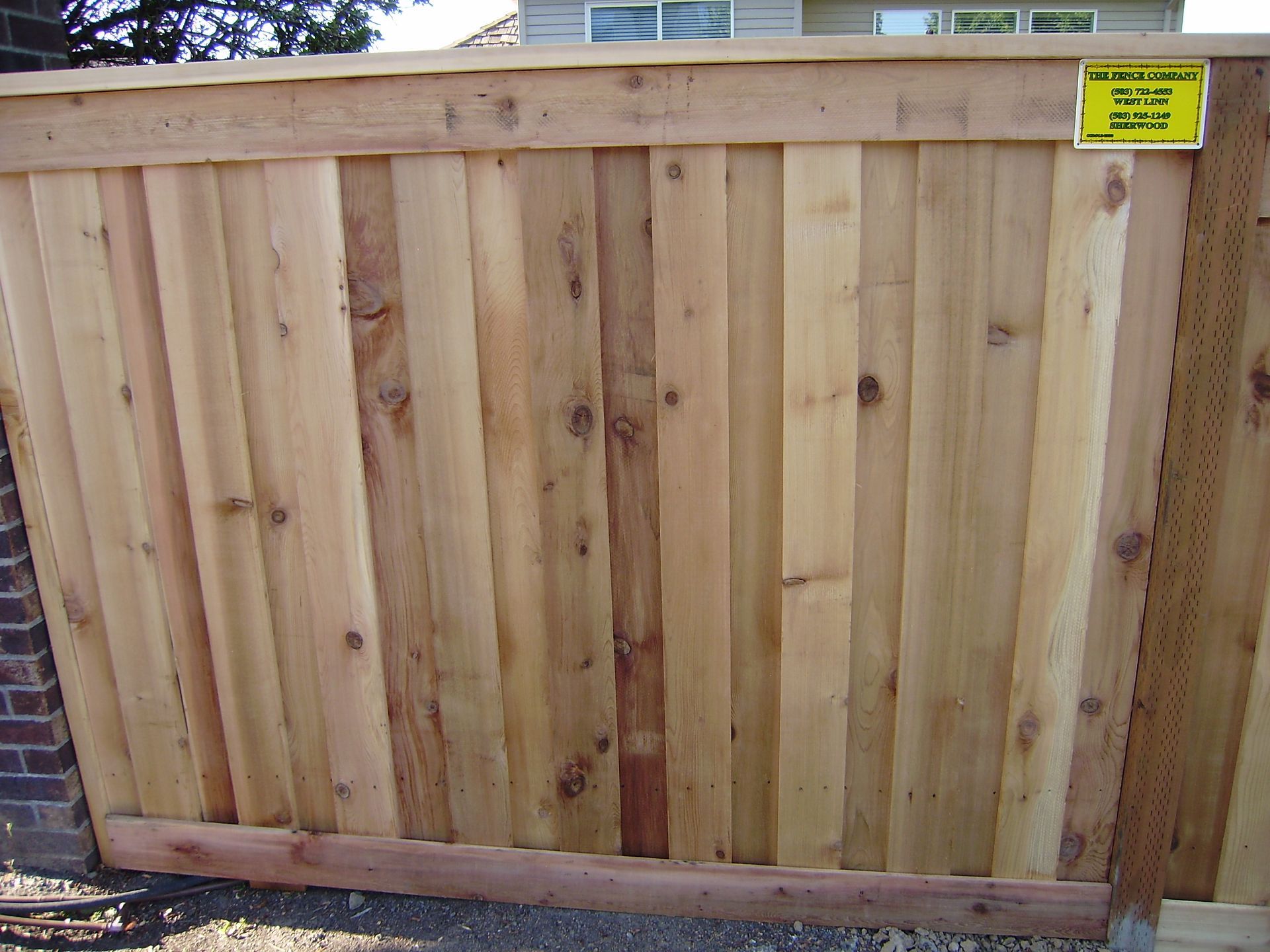 A wooden fence with a yellow sign on it
