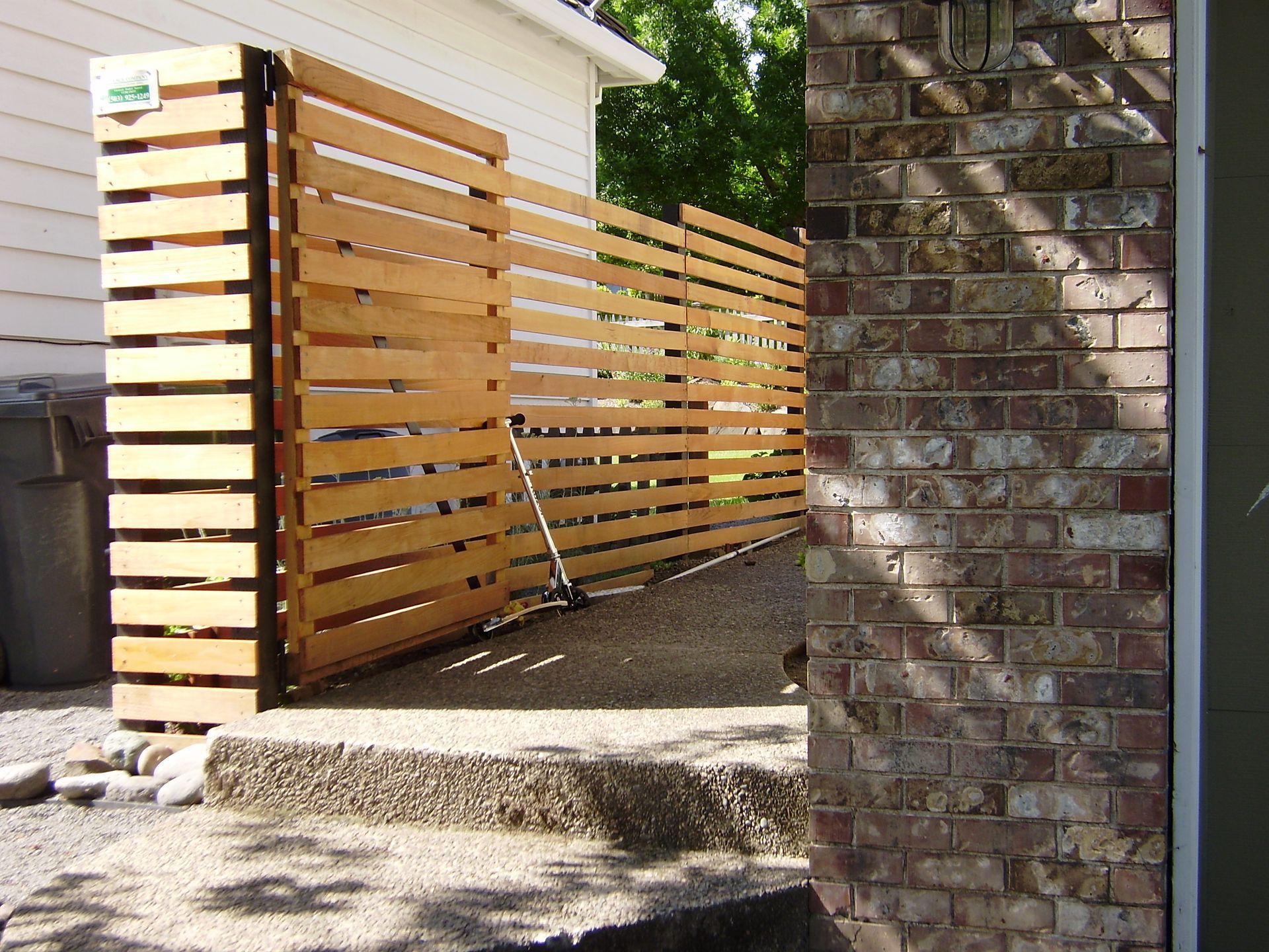 A wooden fence is next to a brick wall