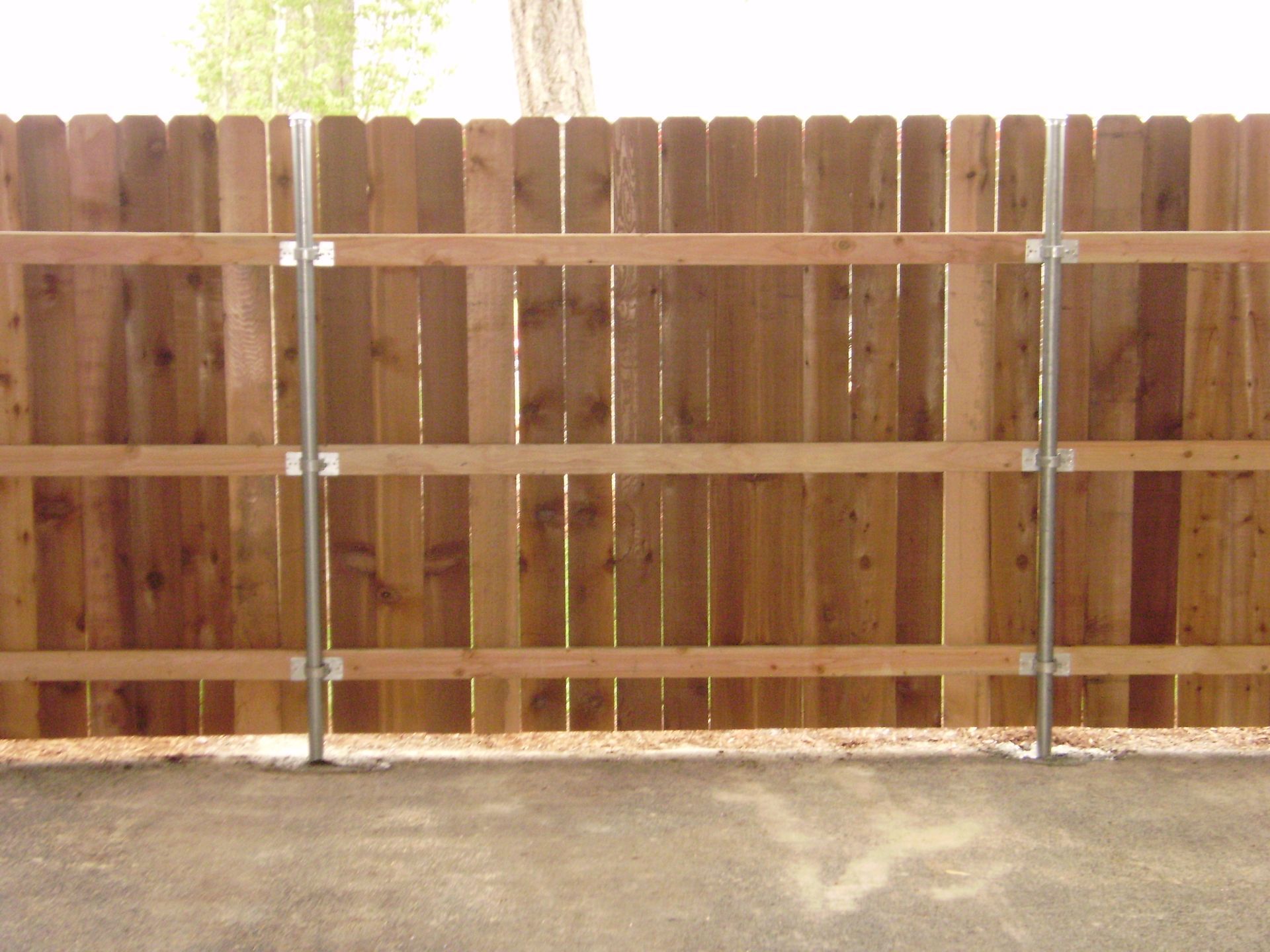 A wooden fence is sitting on top of a gravel driveway