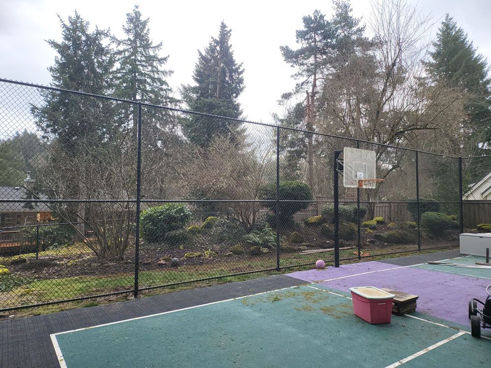 A basketball court with a fence and trees in the background