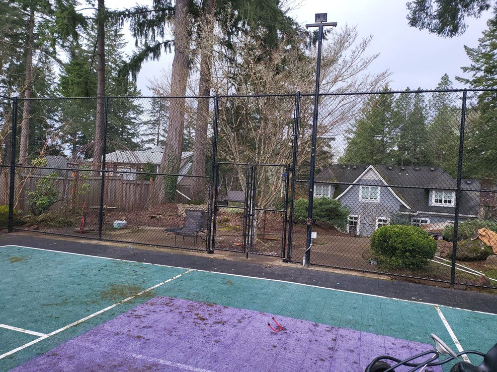 A tennis court with a fence and a house
