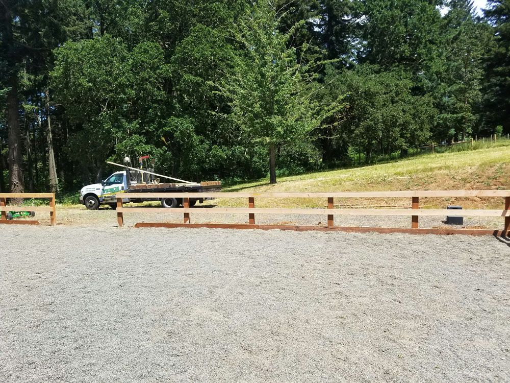 A white truck is parked in a gravel lot next to a wooden fence