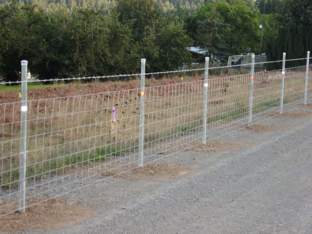 A barbed wire fence along the side of a road