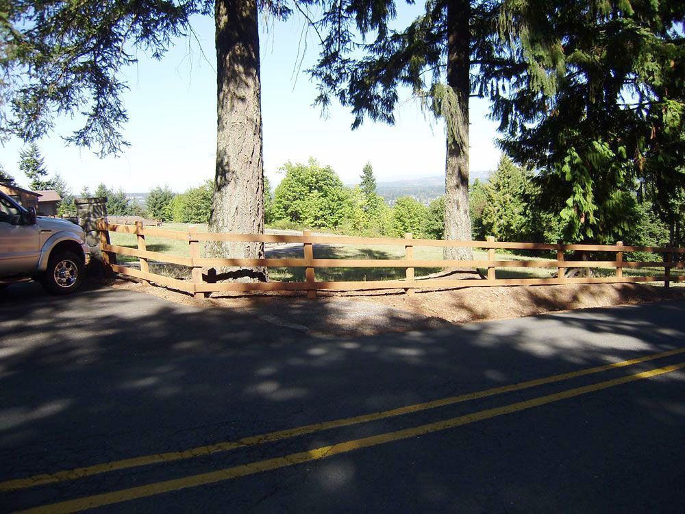 A car is parked on the side of the road next to a wooden fence