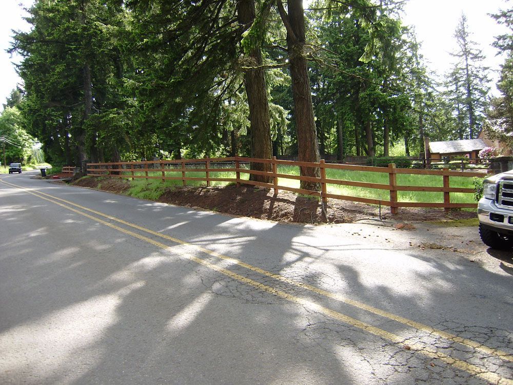 A truck is parked on the side of the road next to a wooden fence.