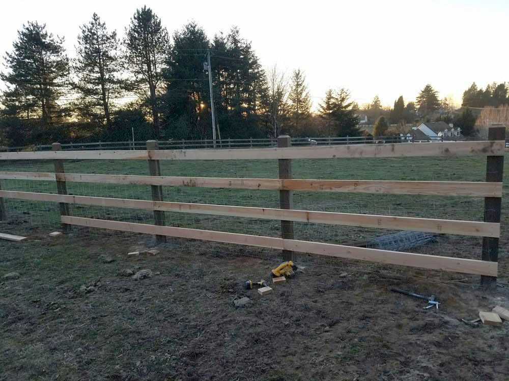 A wooden fence is being built in a field
