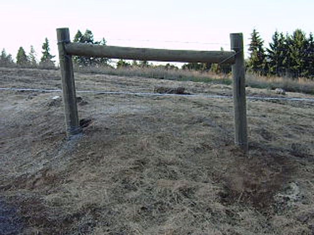 A wooden fence is sitting in the middle of a dirt field