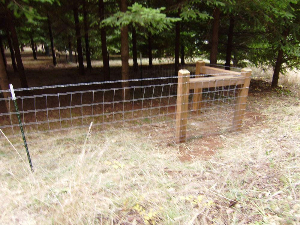 A fence with a wooden post in the middle of a field