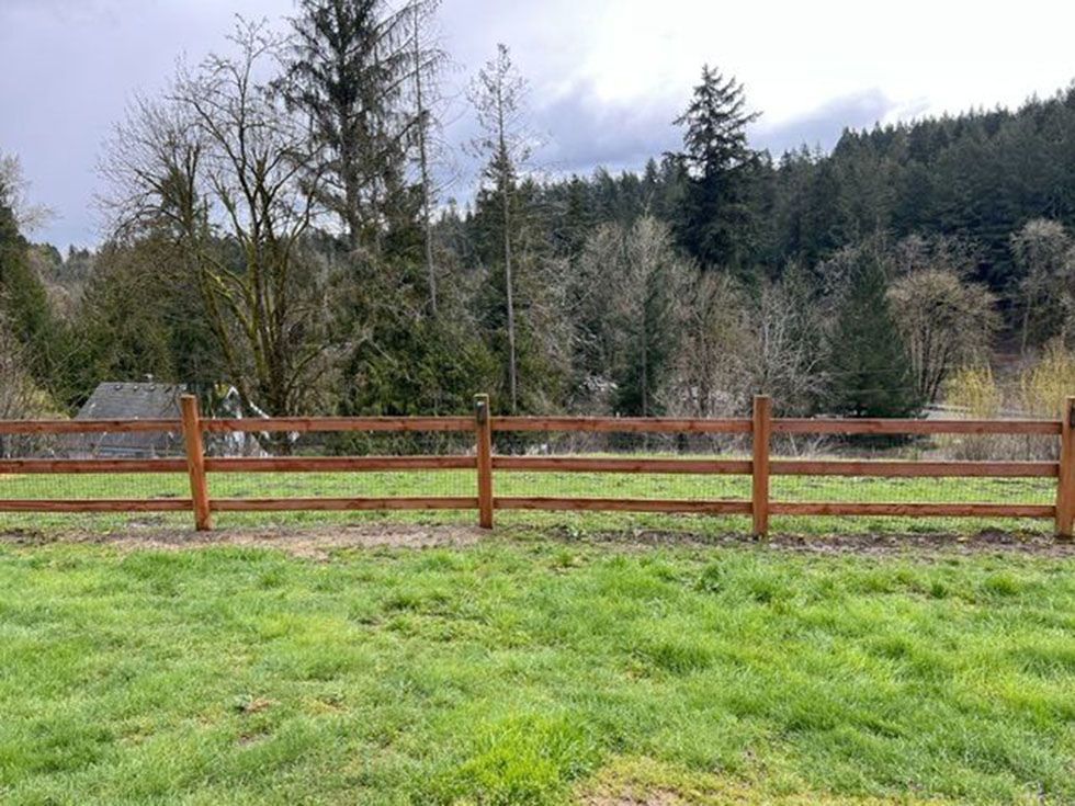 A well-built wooden fence surrounds a grassy field
