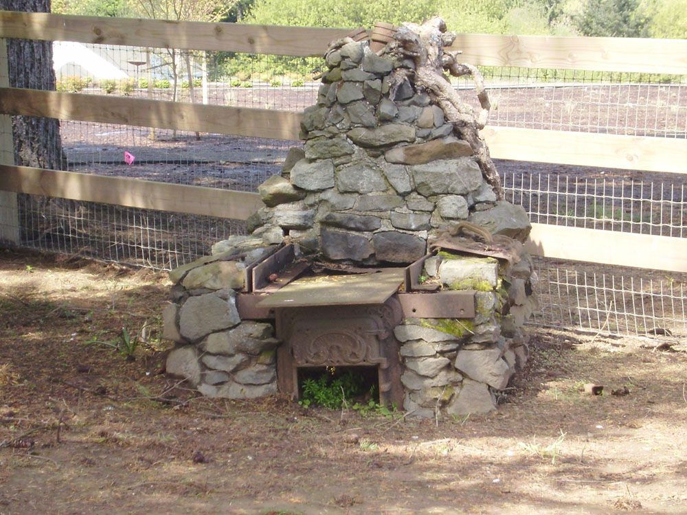 A stone fireplace with a wooden fence in the background
