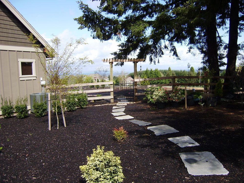 A stone walkway leads to a fence and a house