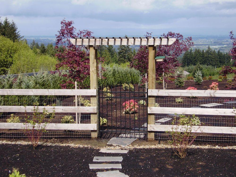 A wooden fence with a metal gate leading to a garden