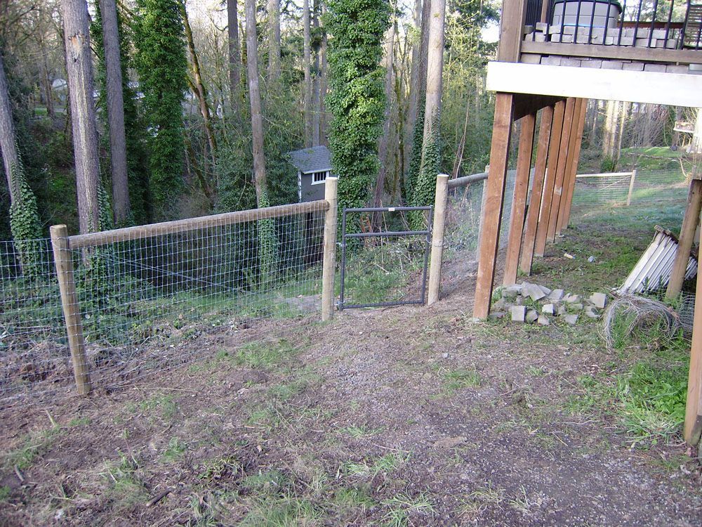 A wooden fence with a gate in the middle of a forest