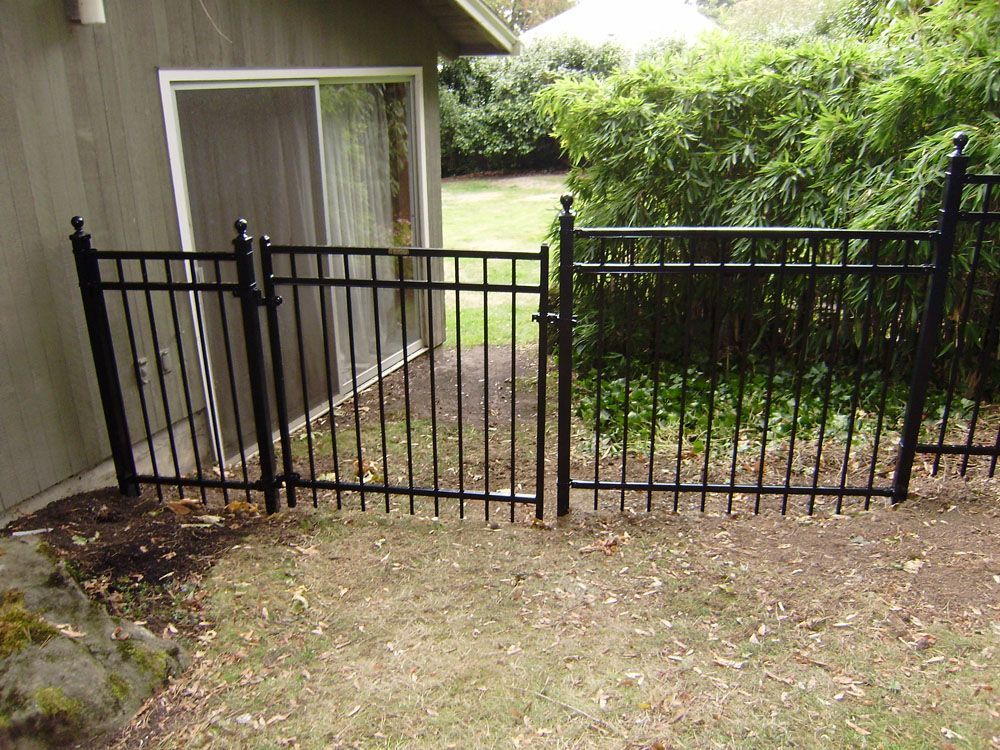 A black wrought iron fence with a gate in front of a house