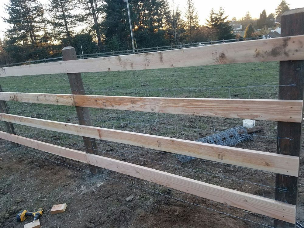 A wooden fence is being built in a field.