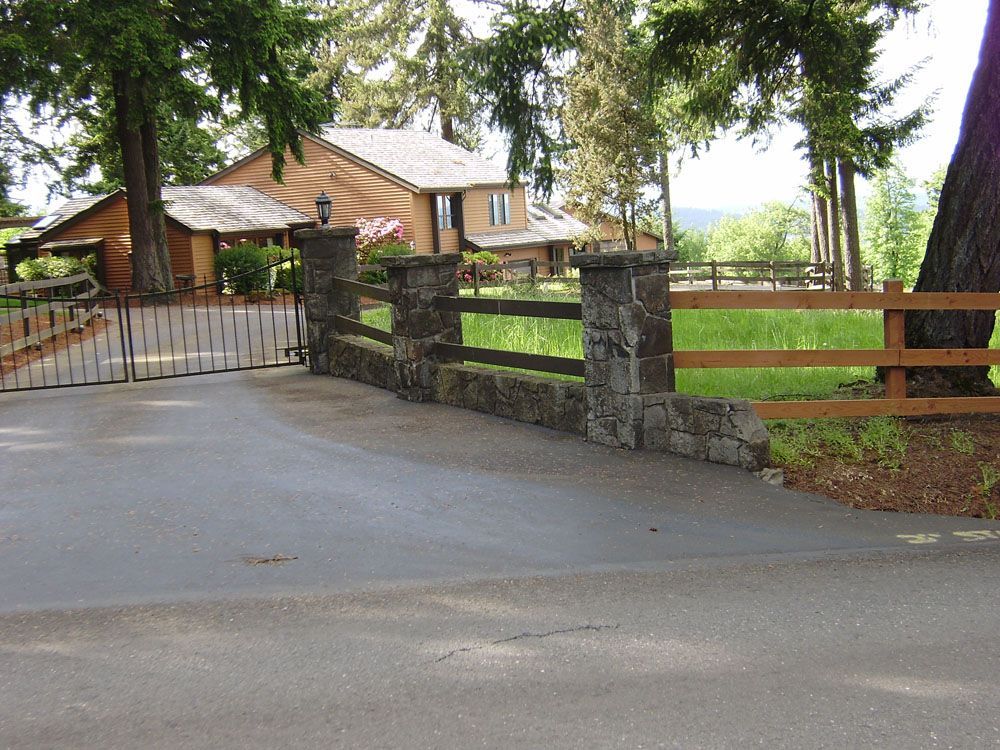 A driveway leading to a house with a wooden fence.