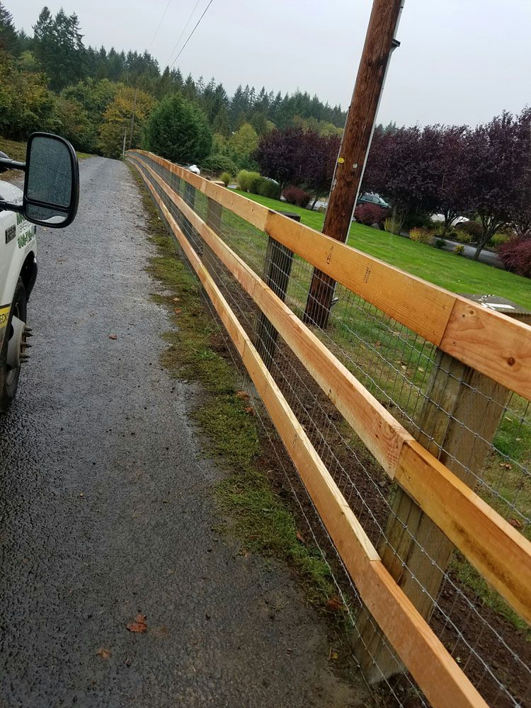 A truck is parked next to a wooden fence on the side of a road.