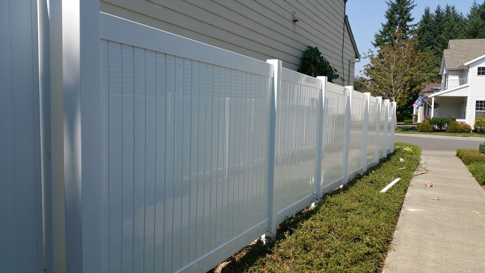 A white fence along a sidewalk next to a house