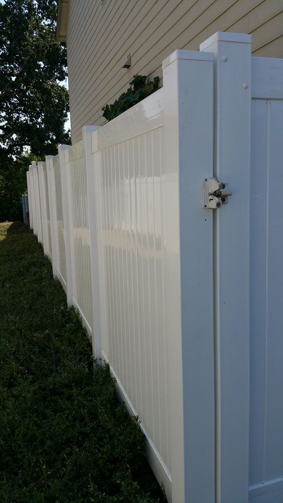A white vinyl fence with a gate in front of a house